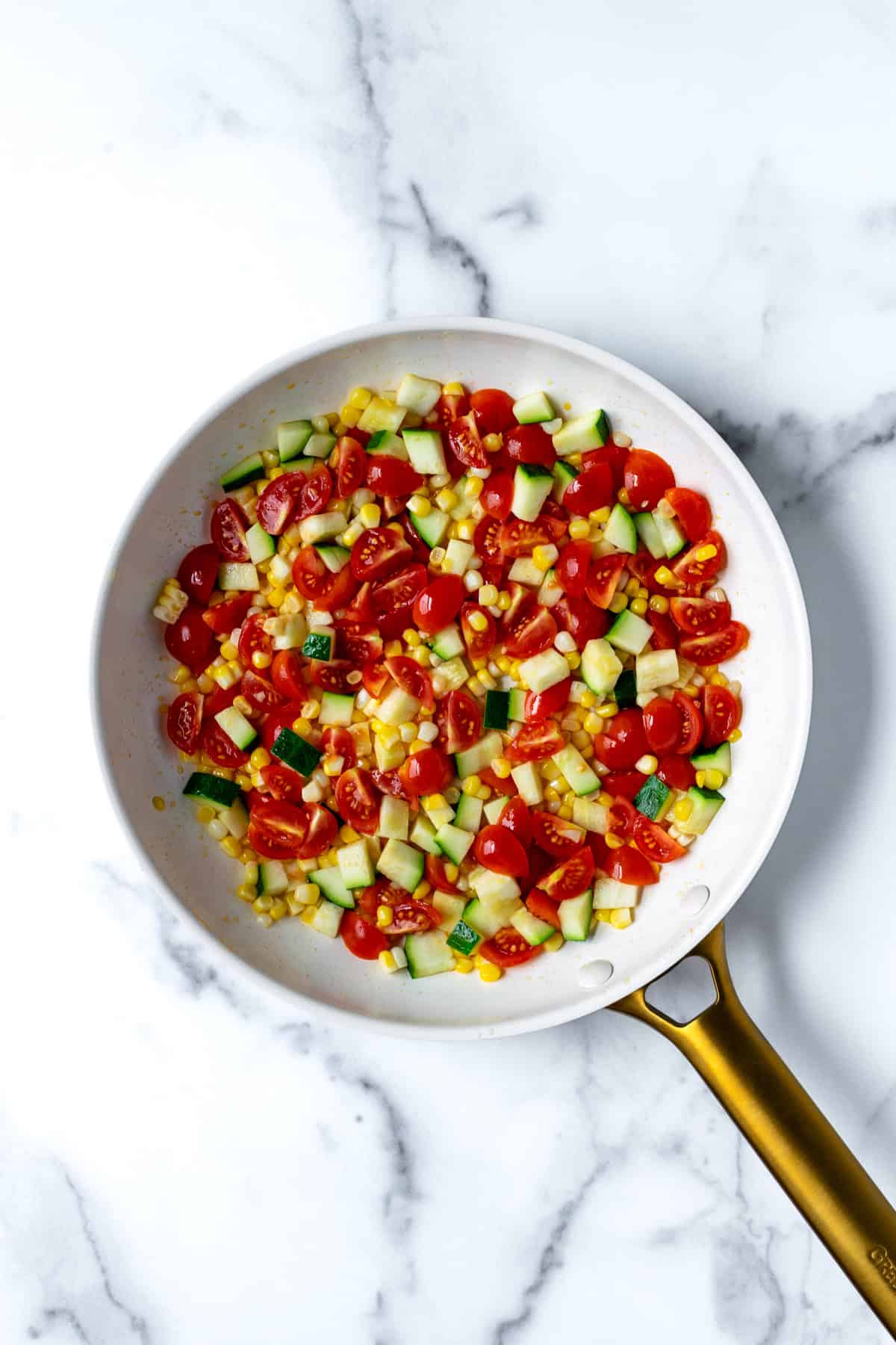 Sauteed summer veggies in a white skillet.