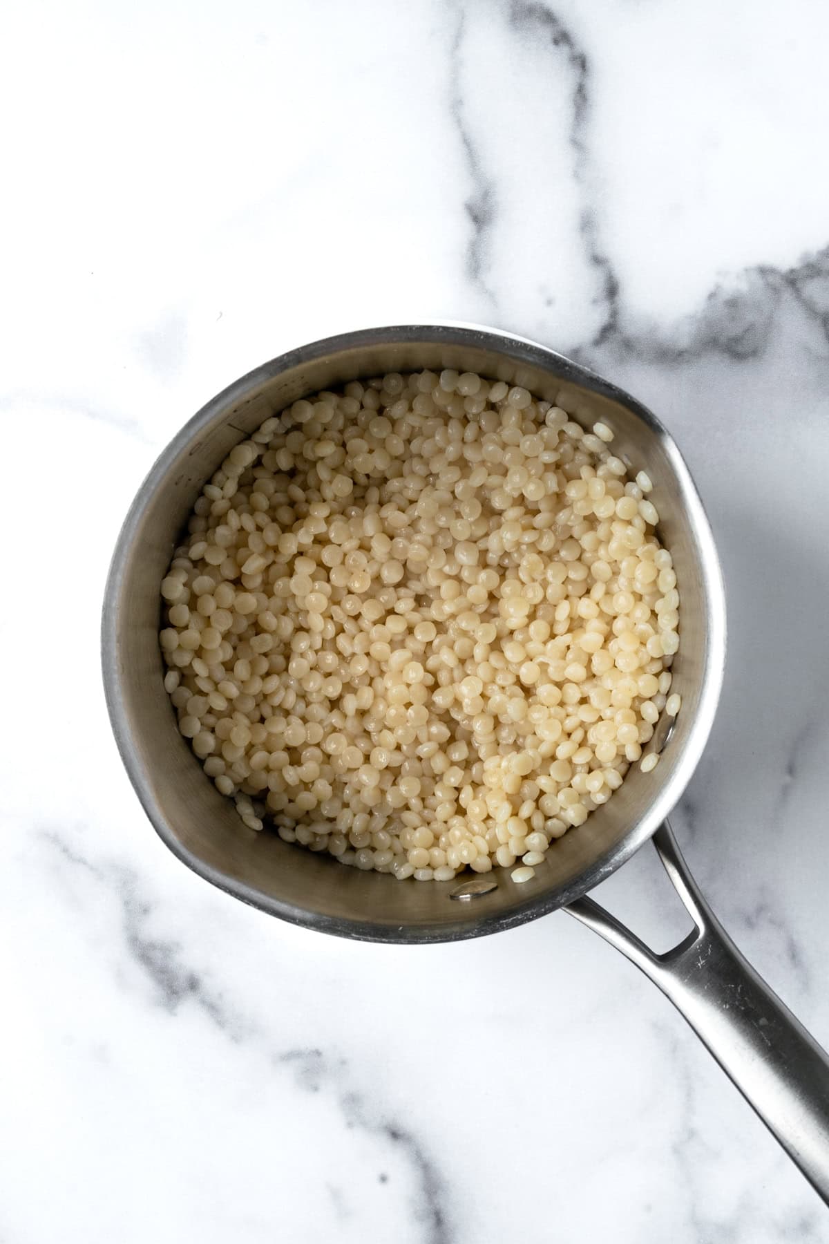 Cooked Pearl Couscous in a stainless steel pot.
