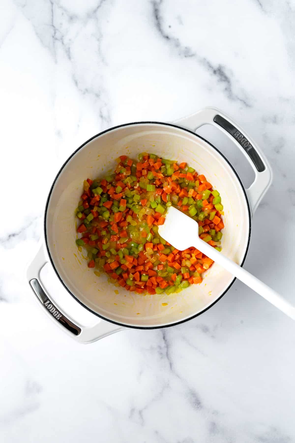 Sautéed carrots, celery, onion, and garlic in a white dutch oven.