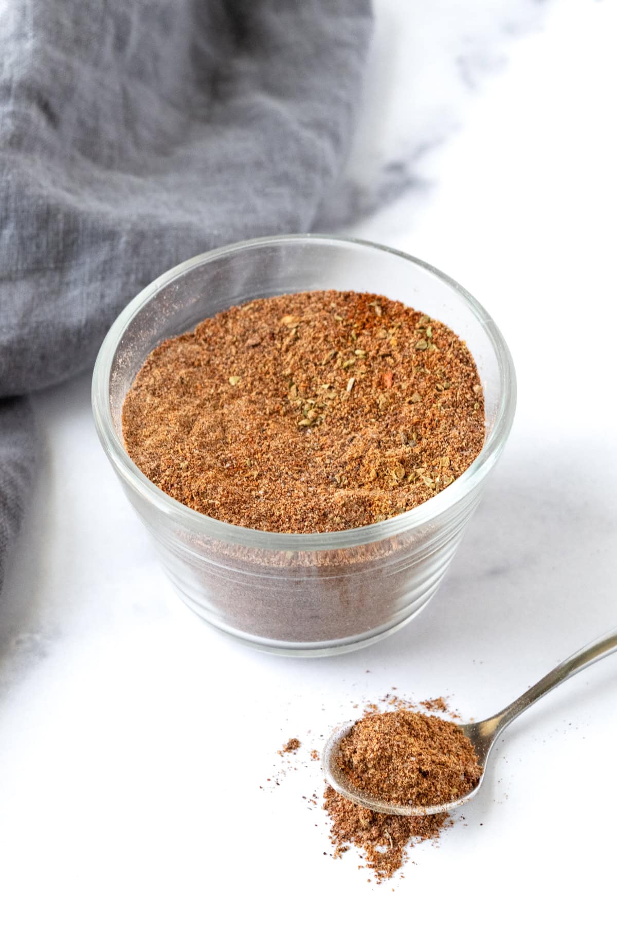 A small glass bowl with homemade Ground Turkey Taco Seasoning on a marble countertop.