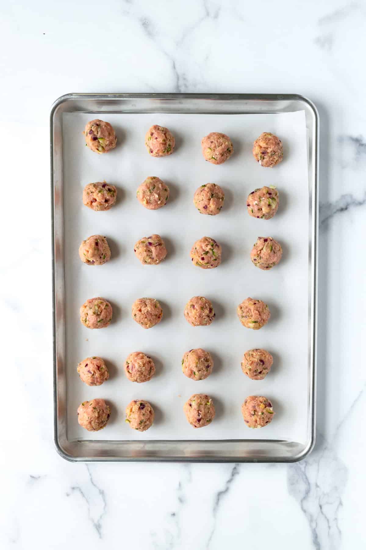 Baked Turkey Meatballs with Zucchini on a baking sheet ready to bake.