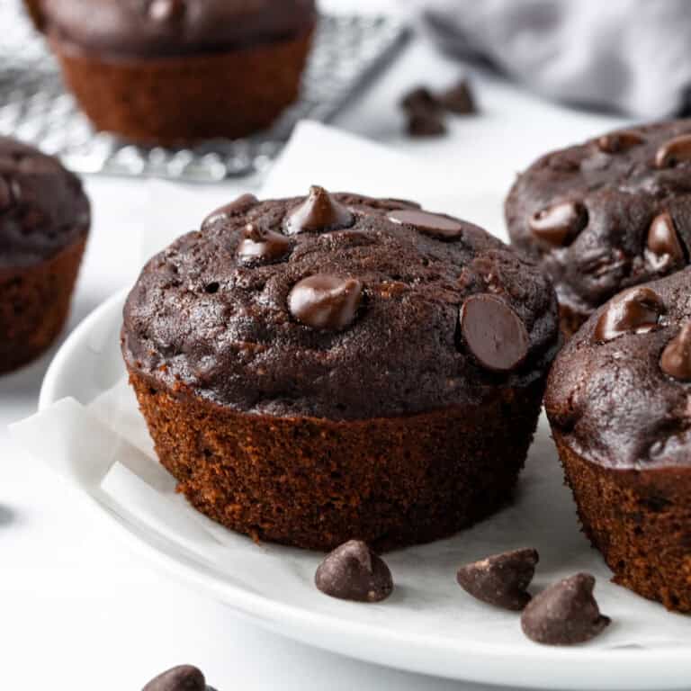 Zucchini Chocolate Muffins with chocolate chips on a white plate.