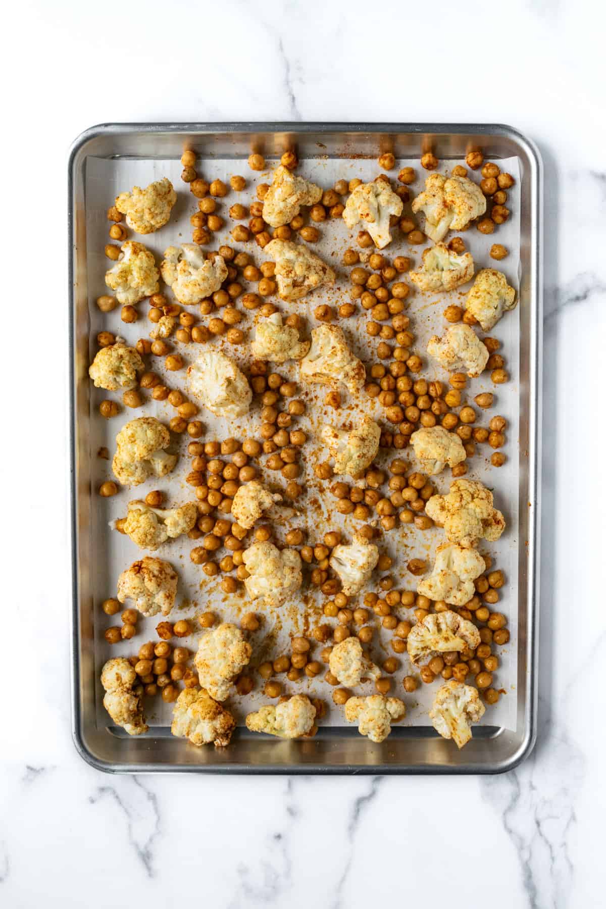 Cauliflower and Chickpeas on a baking sheet ready to be baked.