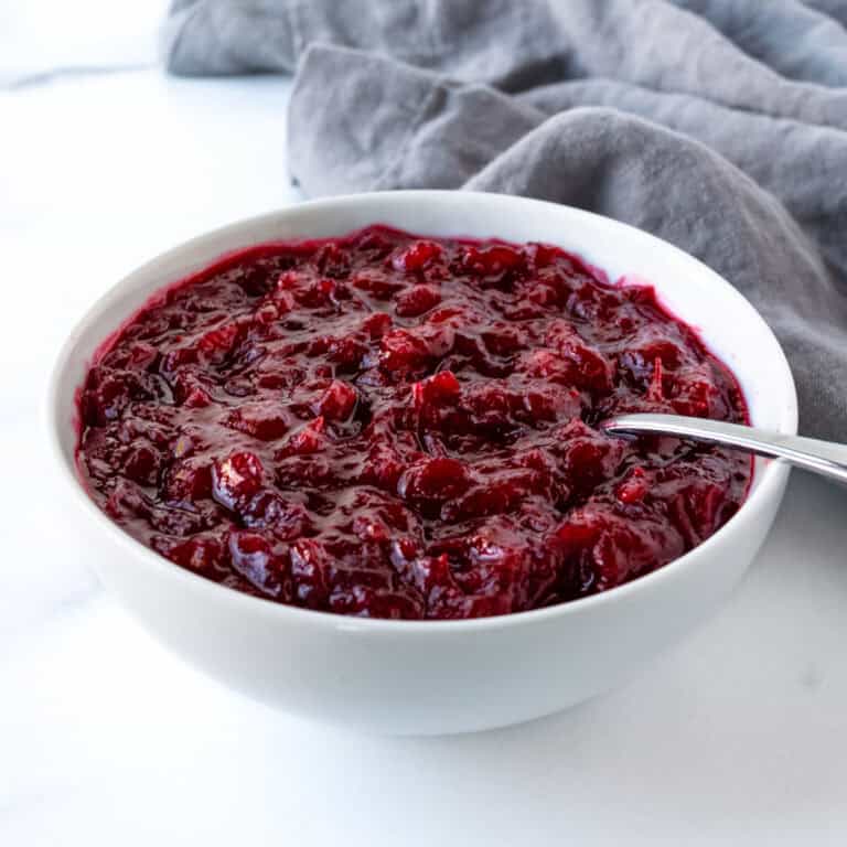 Cranberry Sauce with Honey in a white bowl with a spoon.