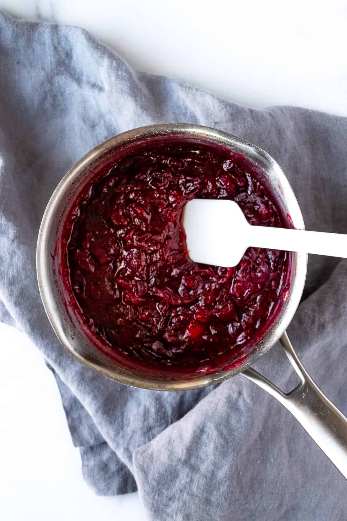 Cranberry Sauce with Honey in a pot with a white silicone spatula.
