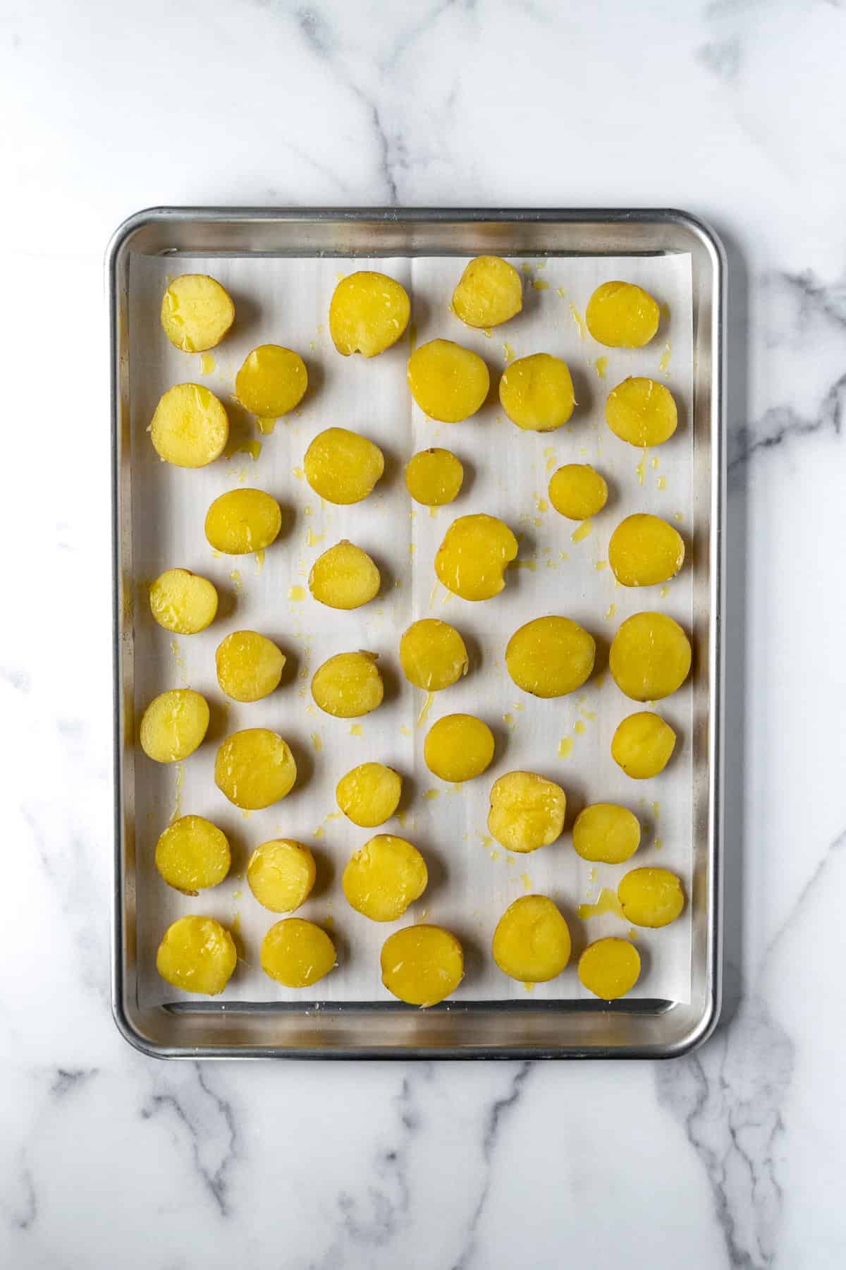 Halved Mini Yellow Potatoes on a parchment lined baking sheet.