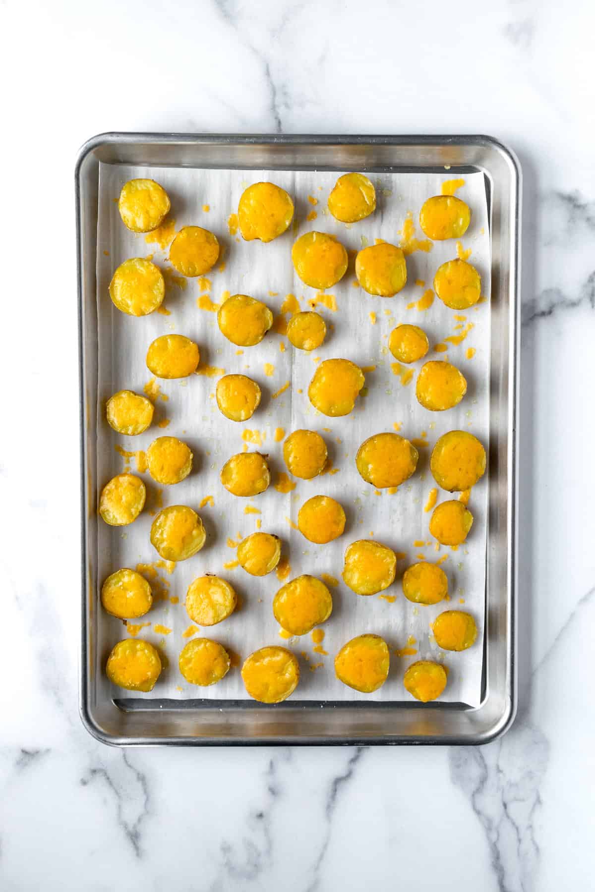 Halved Mini Yellow Potatoes with Cheese on a baking sheet.