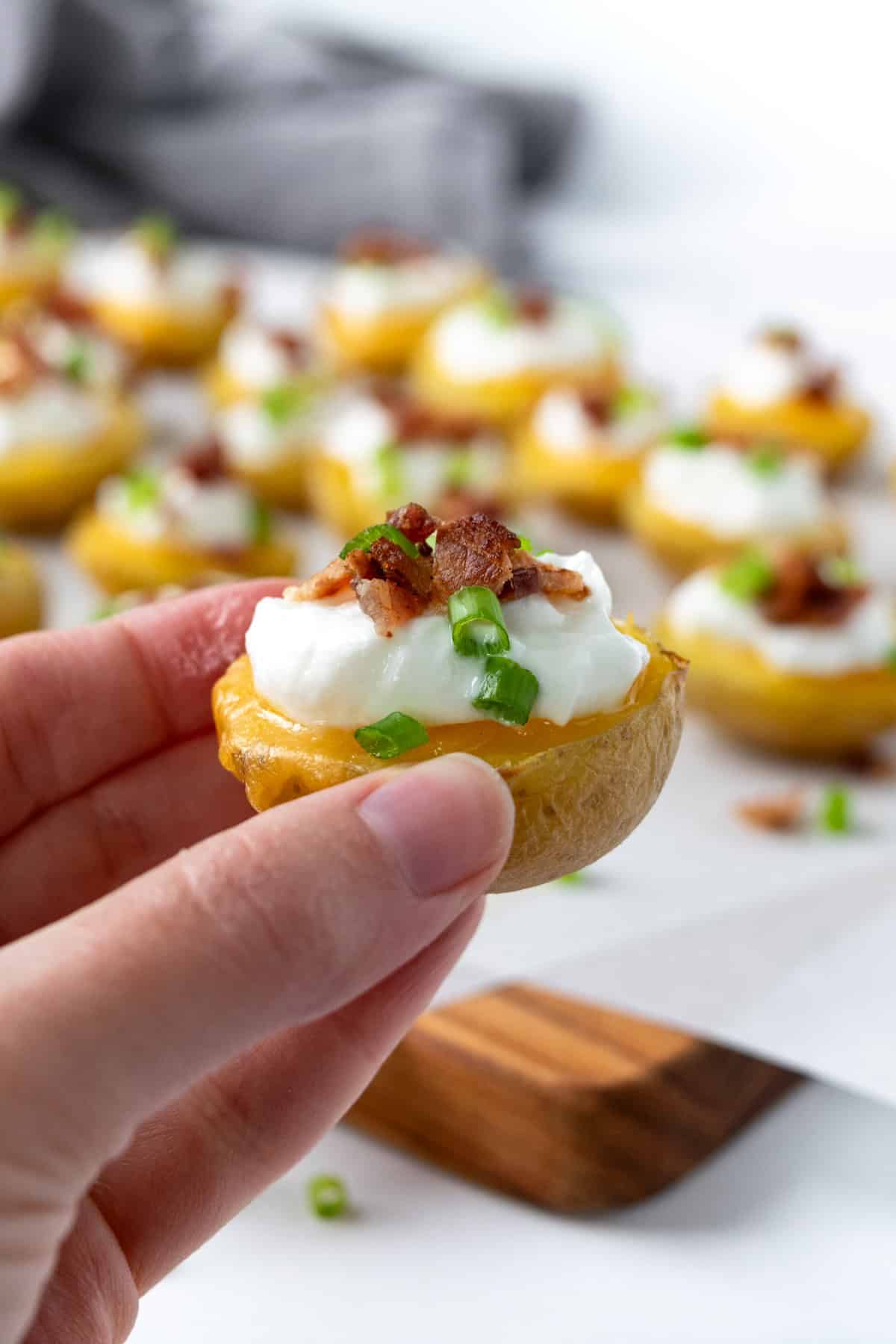 A hand holding a Loaded Baked Potato Bite.
