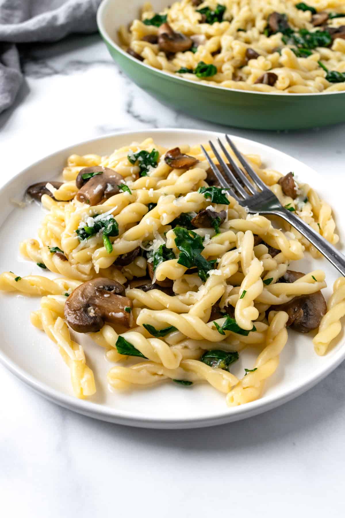 Spinach Mushroom Pasta on a white plate with a fork.