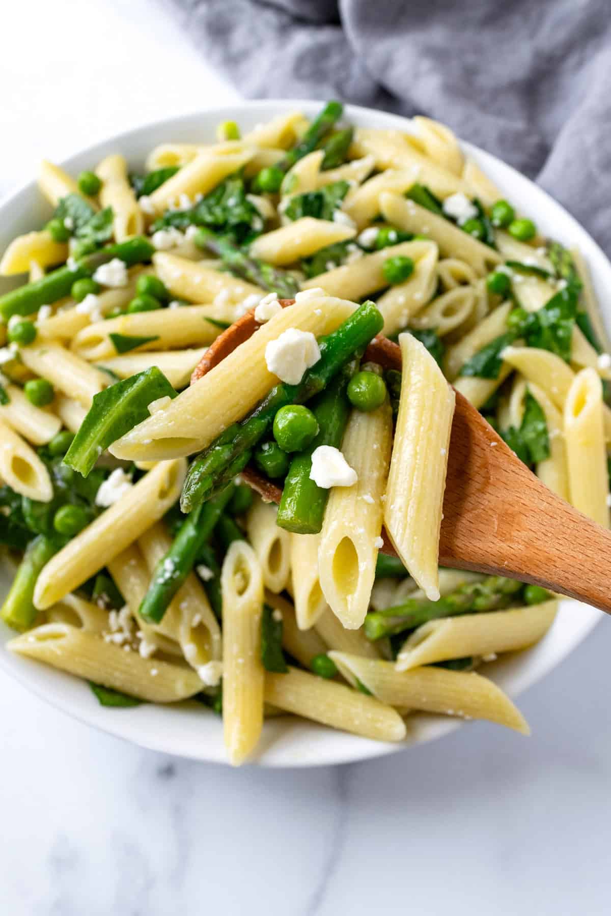 A wooden serving spoon of Primavera Pasta Salad.