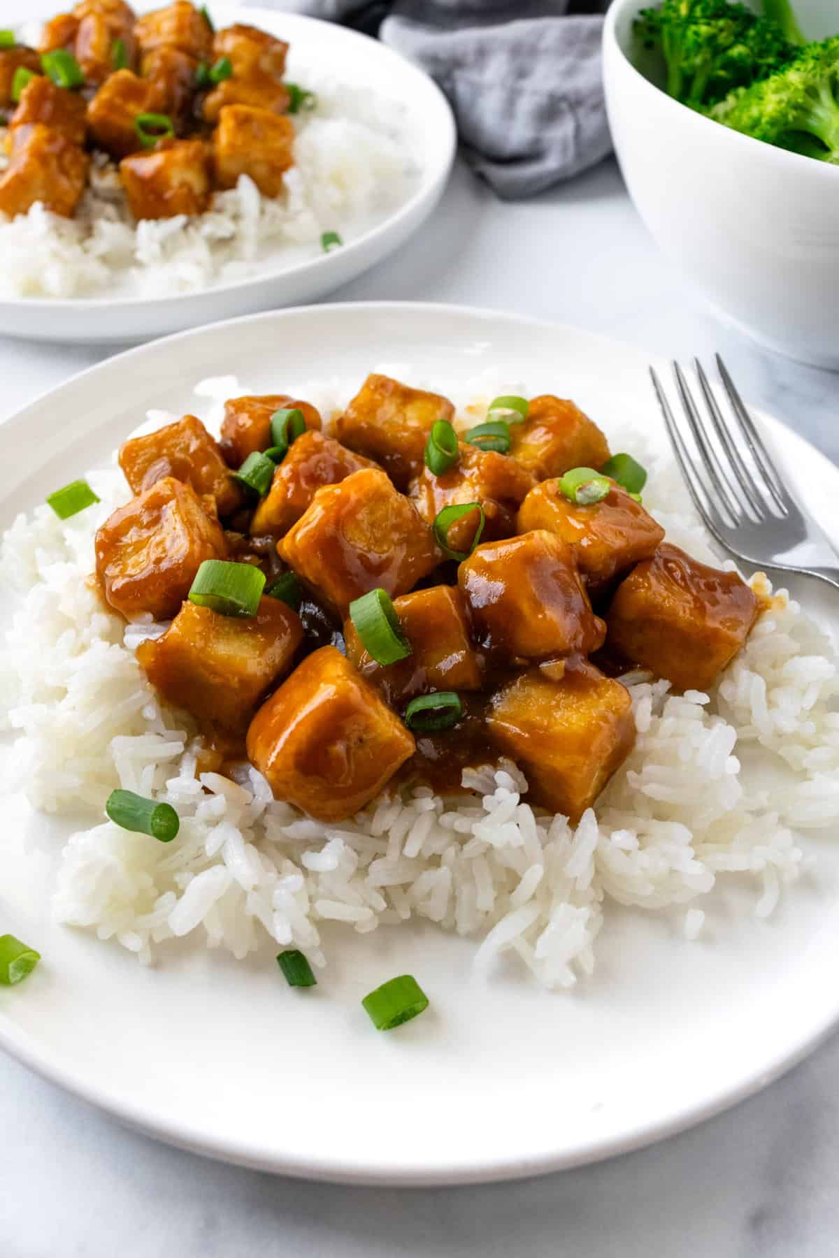 Sticky Orange Tofu on a white rice on a white plate.