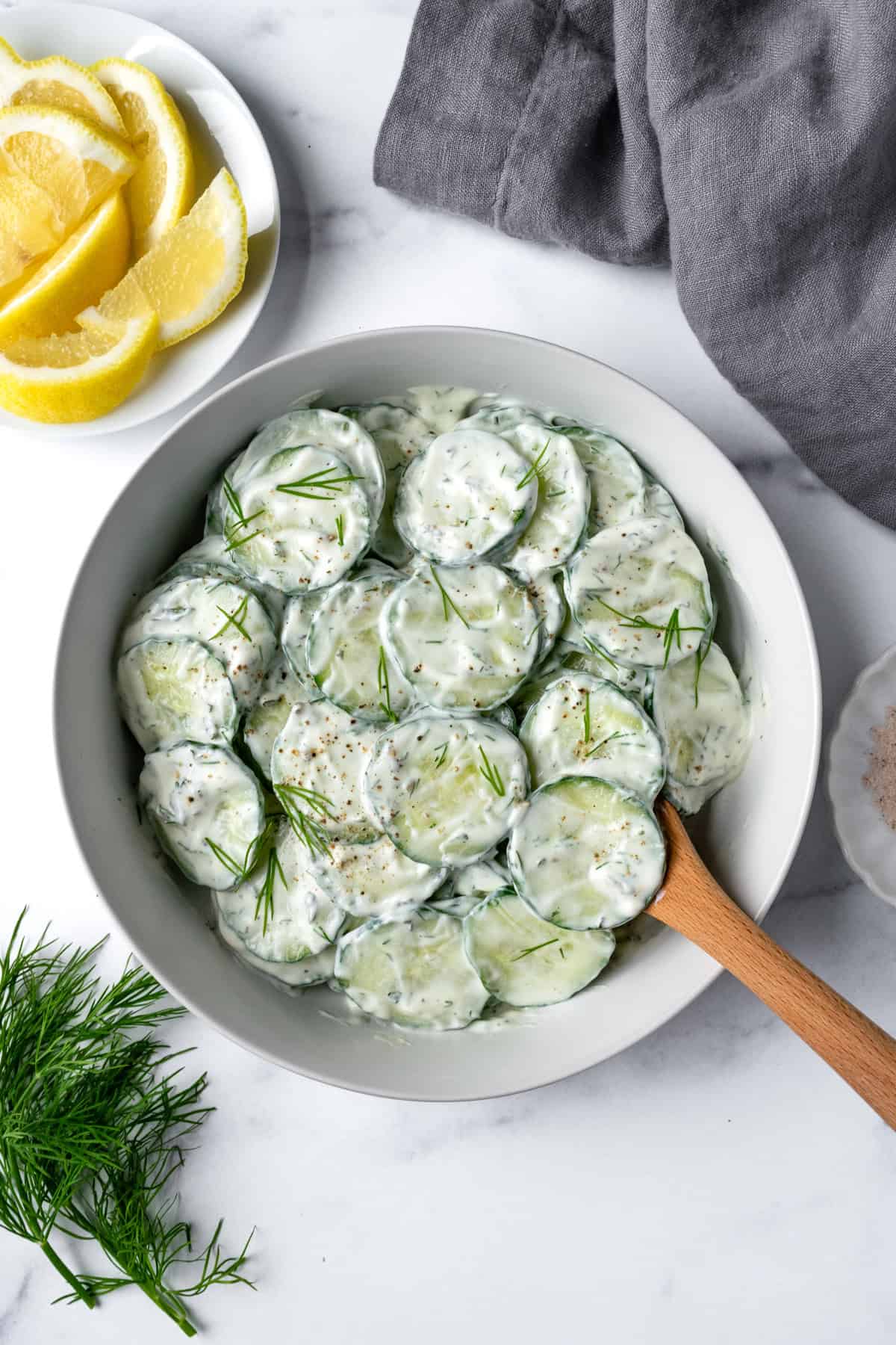 Greek Yogurt Cucumber Salad in a white bowl with a wooden serving spoon.