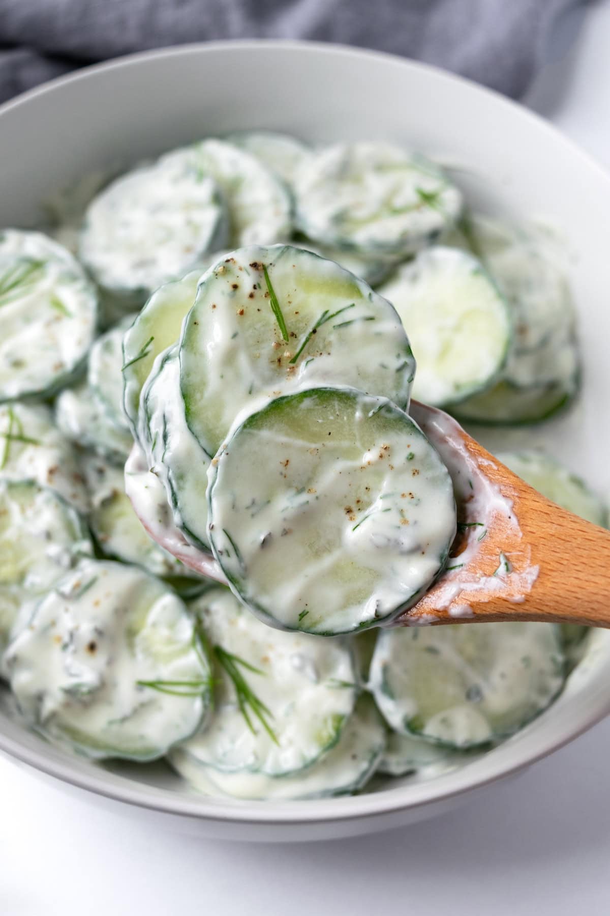 Creamy Cucumber Salad on a wooden spoon.