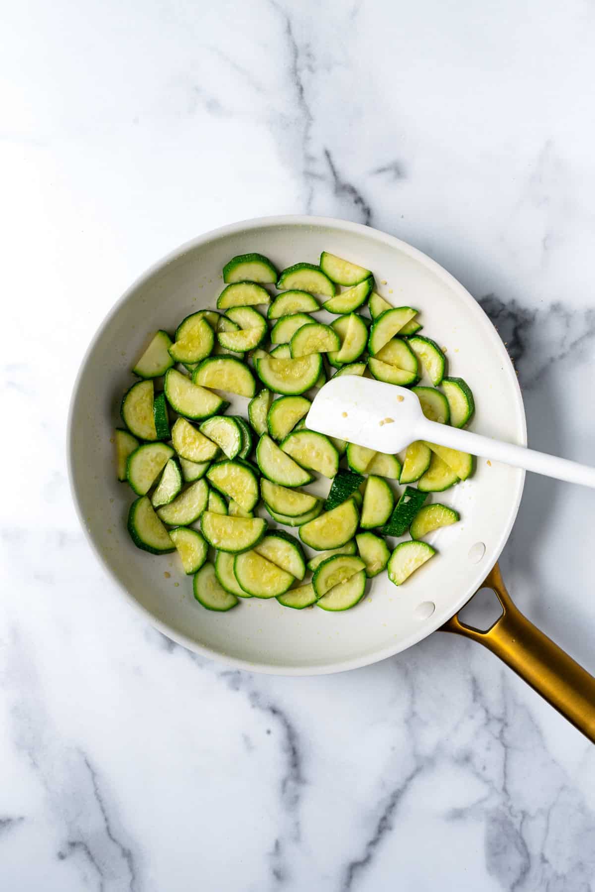 Sautéed Zucchini in a white skillet.