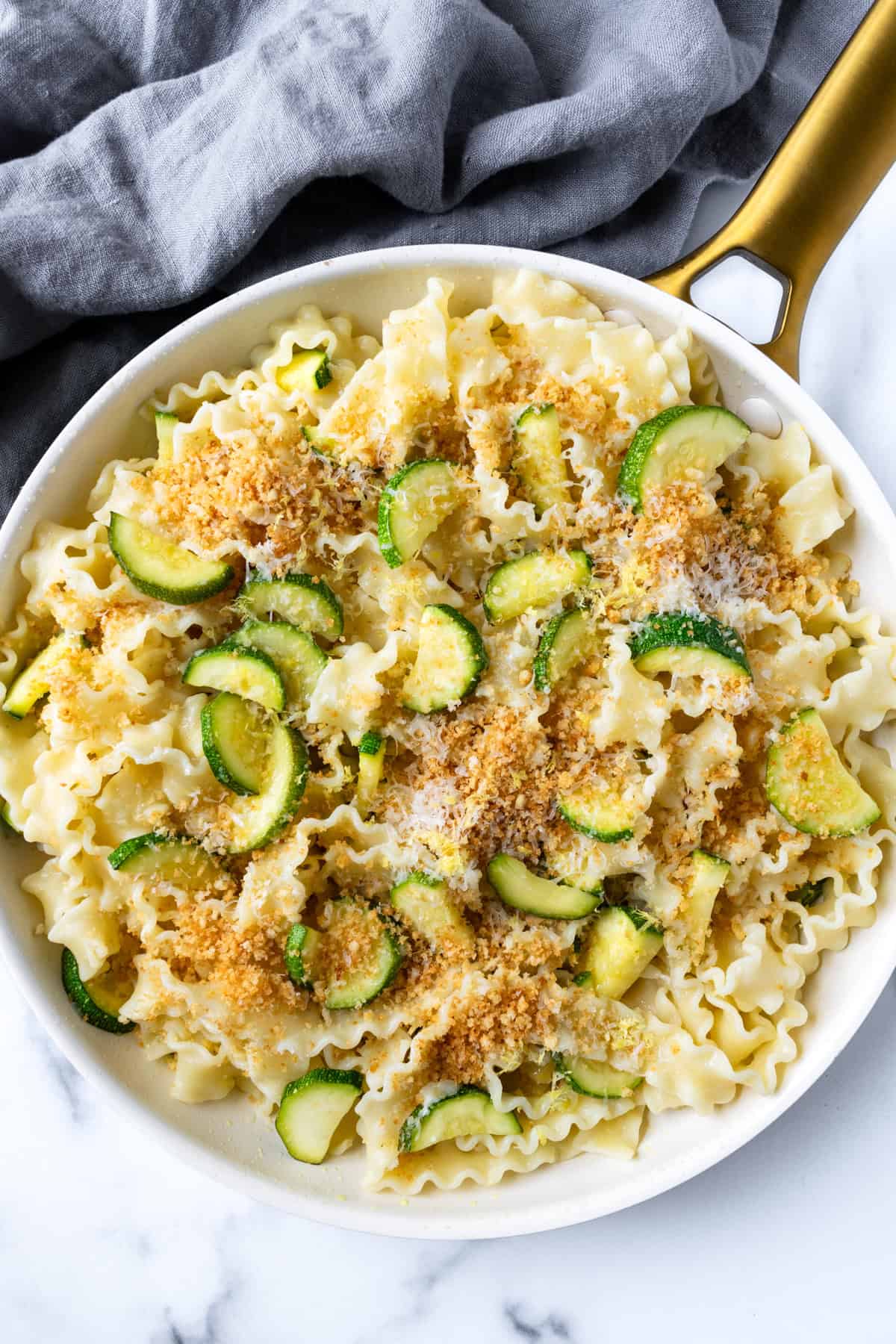 Lemon Zucchini Pasta topped with Garlic Breadcrumbs in white skillet.