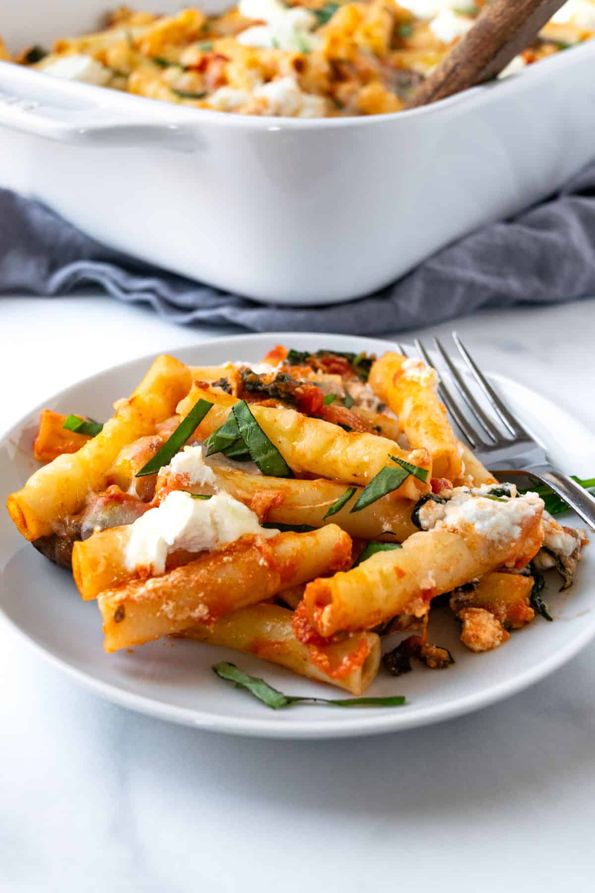 Baked Ziti with Vegetables on a white plate with a fork.