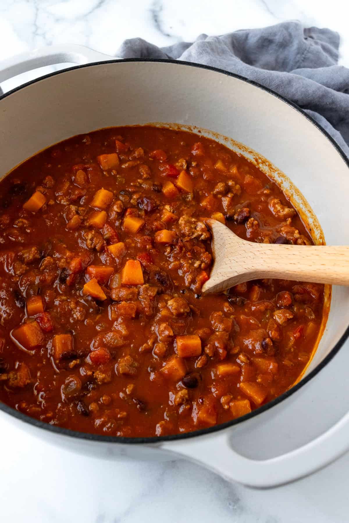 Butternut Squash Chili with Ground Turkey in a Pot with a Wooden Spoon.