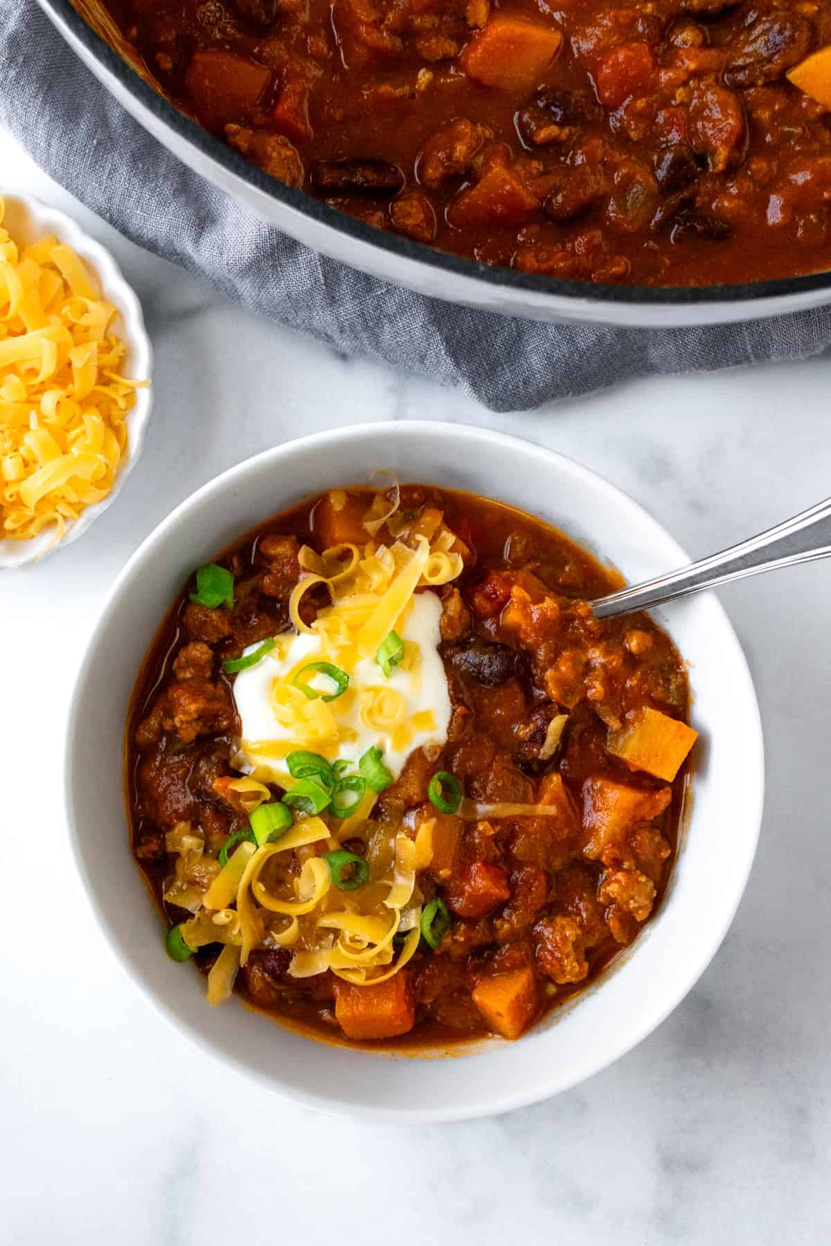 A bowl of Butternut Squash Turkey Chili with Sour Cream and Cheddar Cheese.