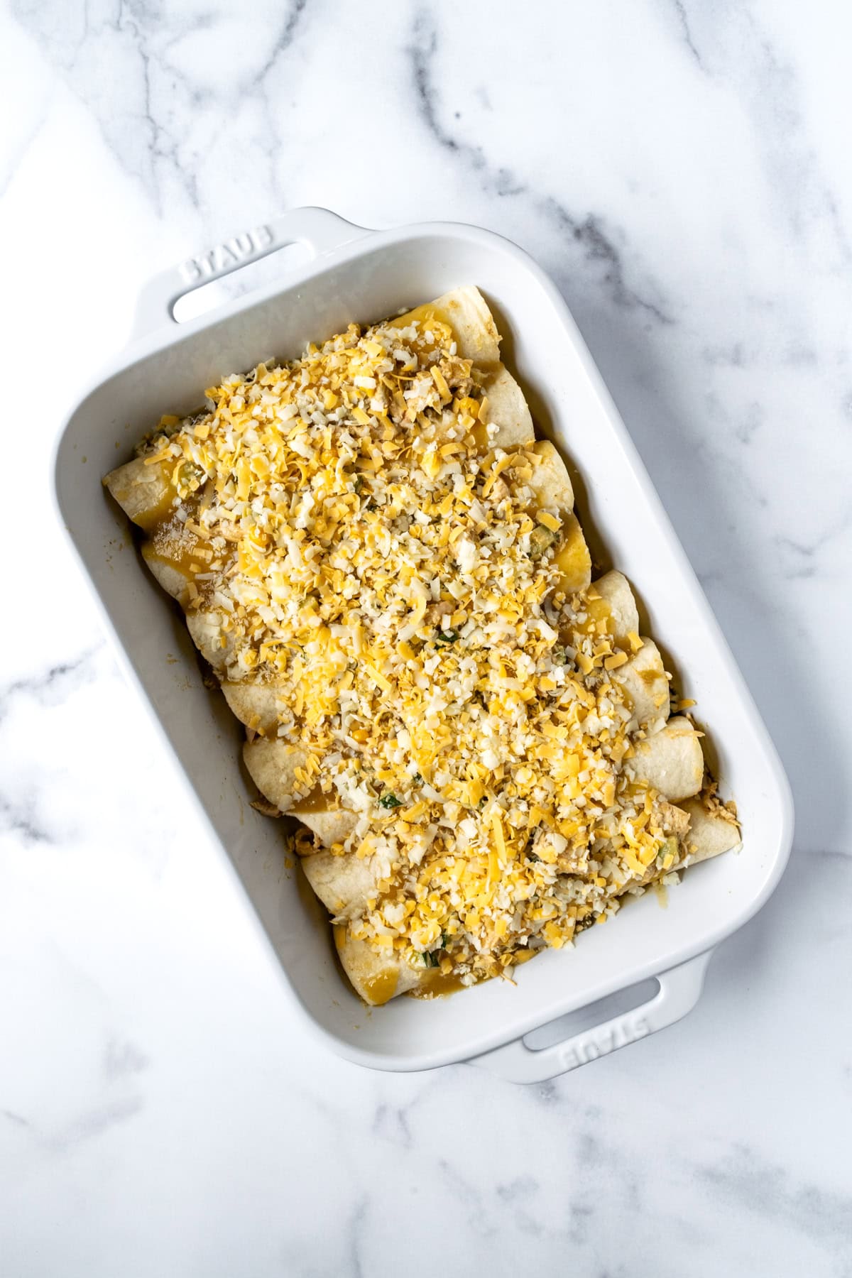 Chicken Enchiladas with Green Sauce ready to bake in a white baking dish.