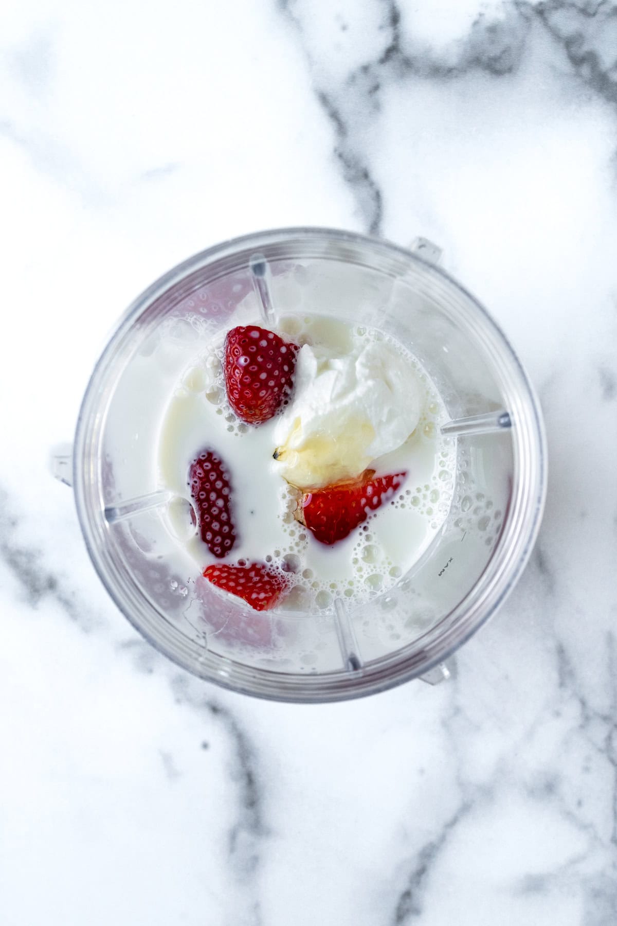 Strawberries, milk, and honey in a blender.