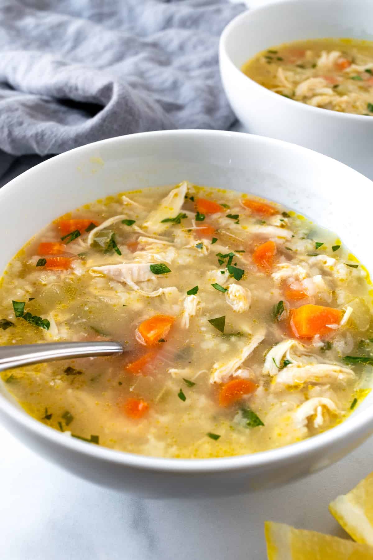 Lemon Chicken Rice Soup in a white bowl with a spoon.