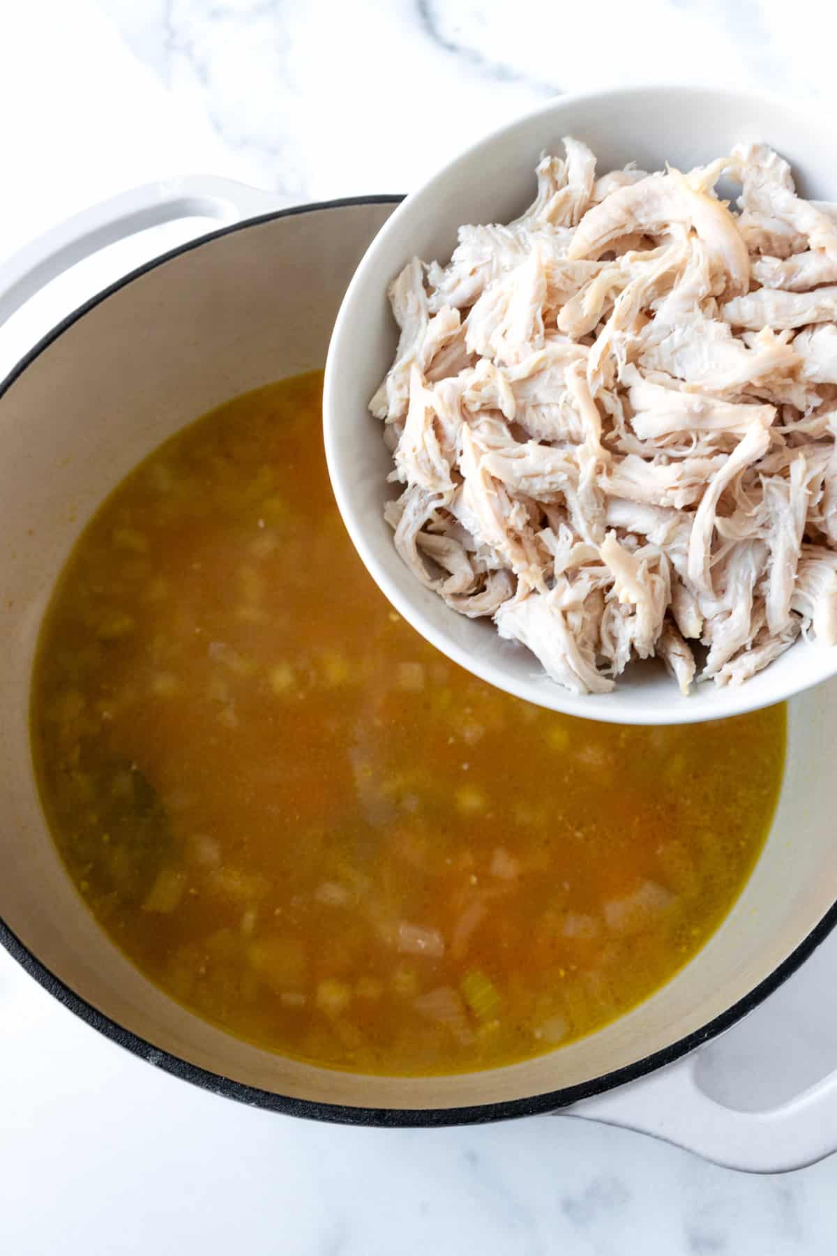 Adding shredded chicken to lemon chicken rice soup.