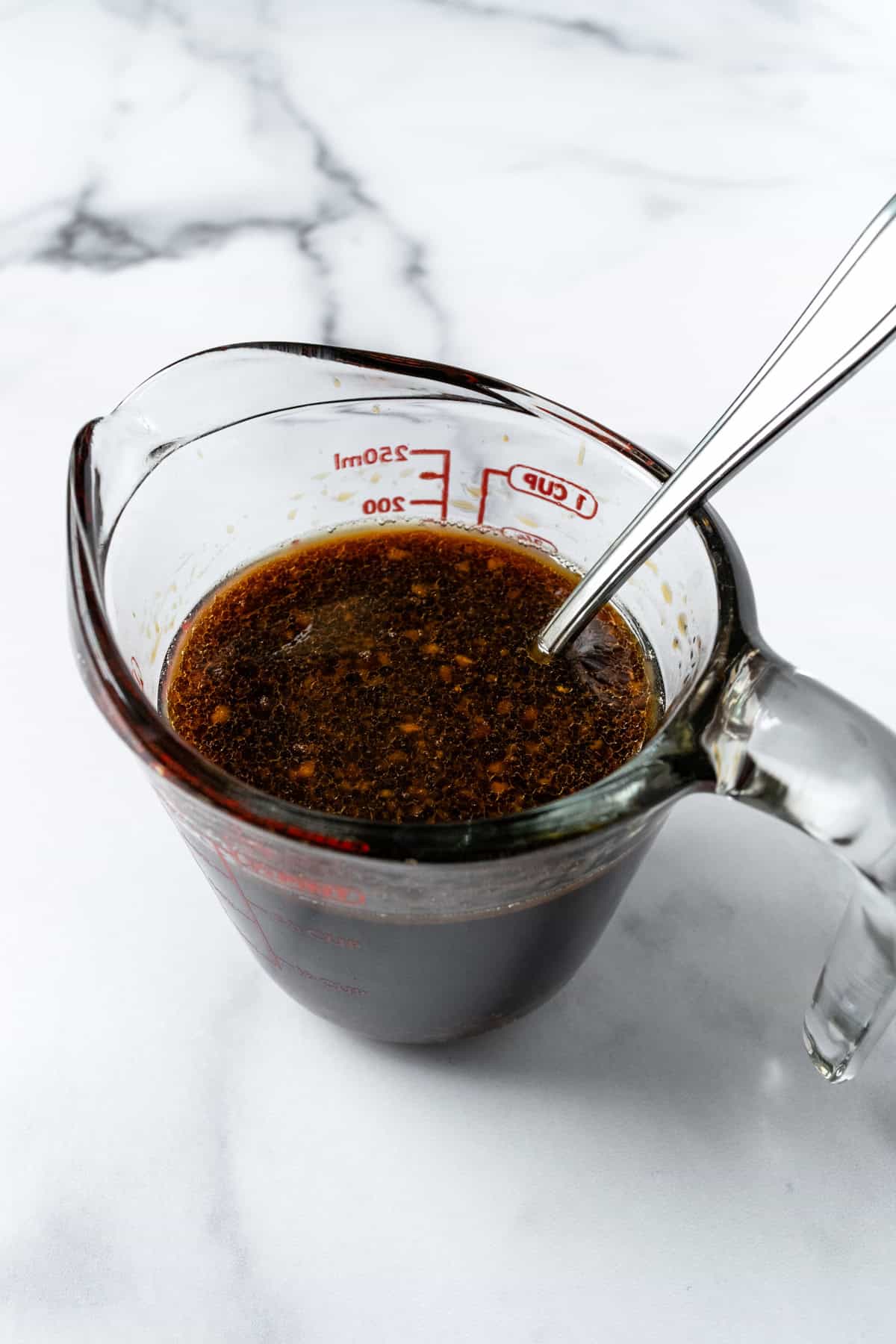 Sauce for Beef and Broccoli in a measuring cup with a spoon.