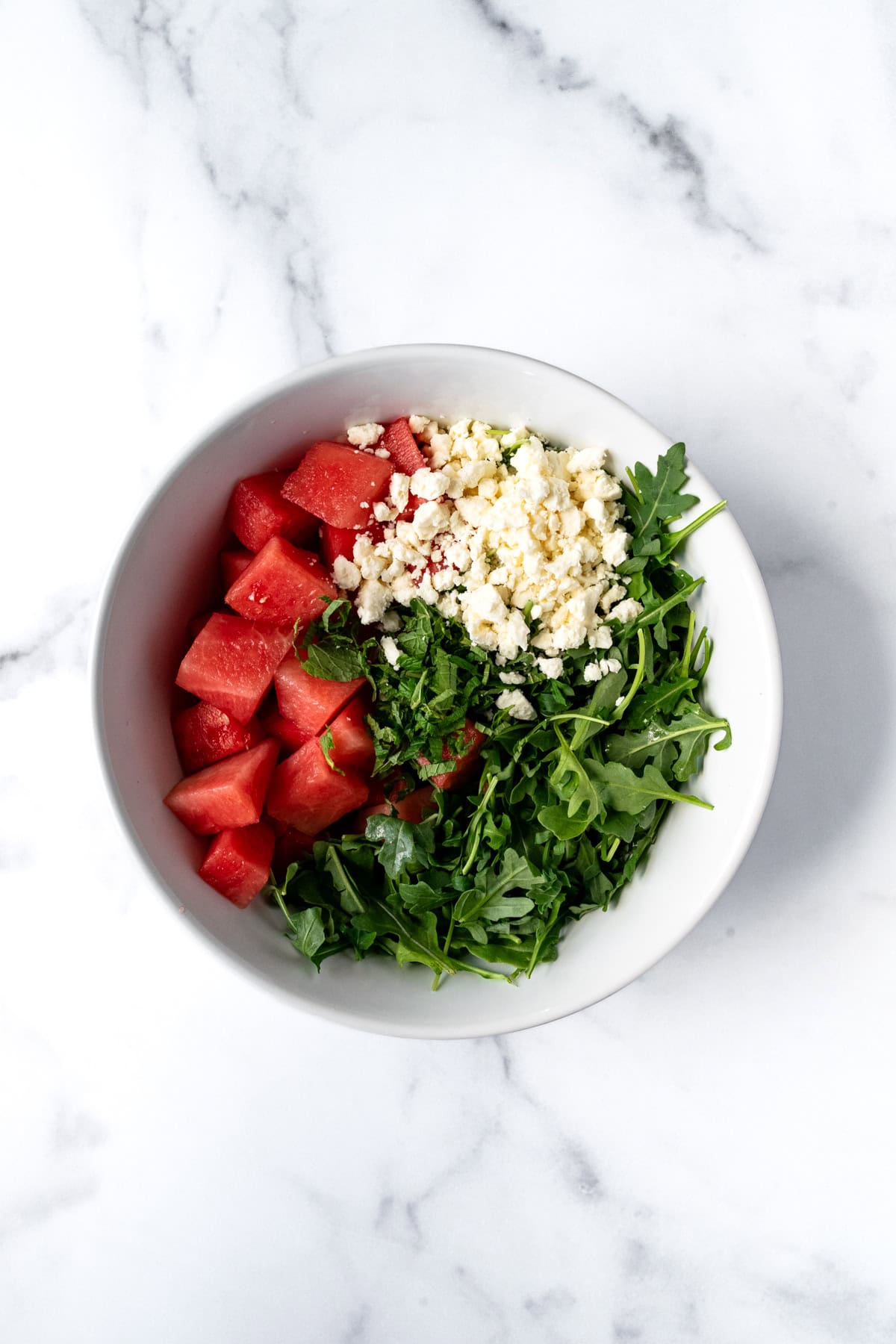 Watermelon Arugula Salad Ingredients in a White Bowl.