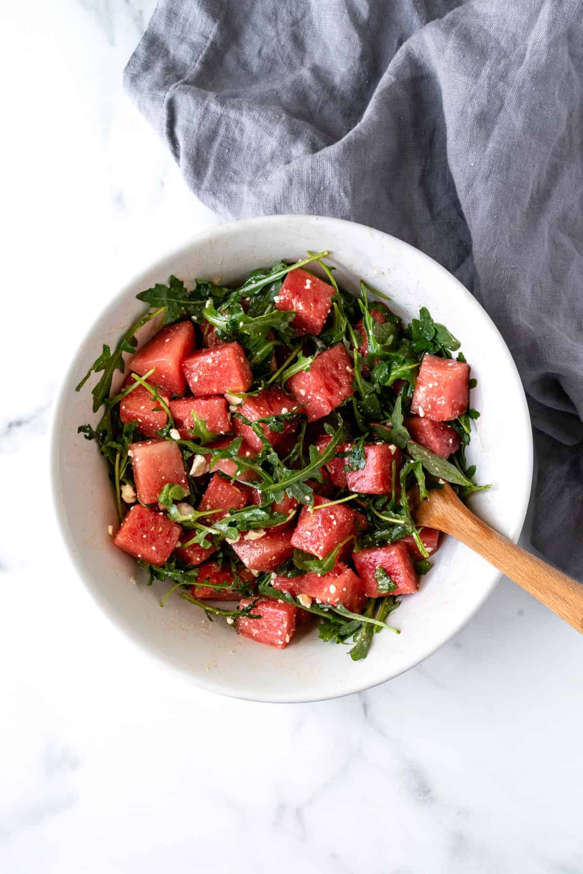 Watermelon Arugula Salad tossed in a white bowl.