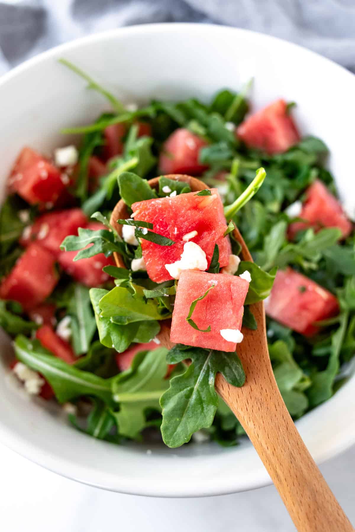 A serving spoonful of watermelon arugula salad.