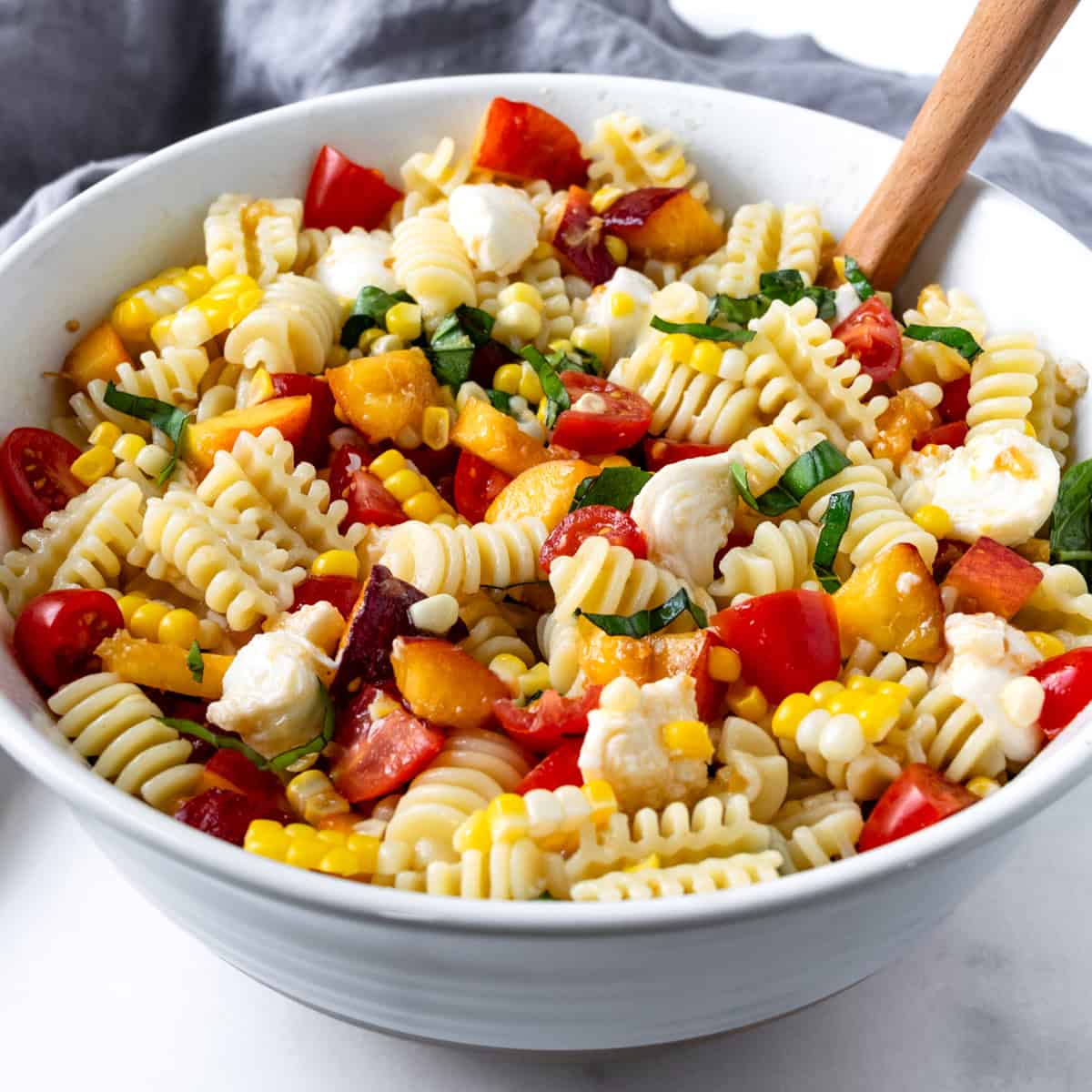 Peach and Corn Pasta Salad in a white bowl.